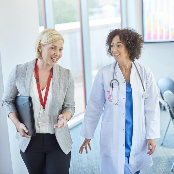 A doctor walks out of a meeting with a colleague